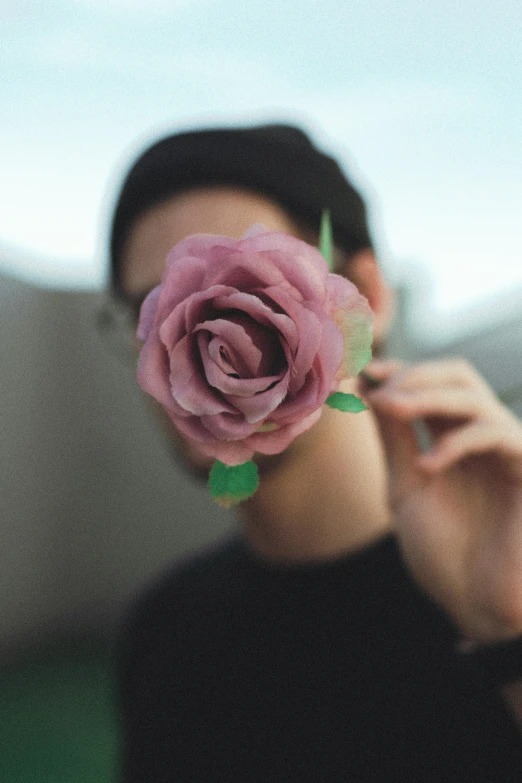 a person holding a flower in front of their face, a colorized photo, trending on pexels, photorealism, rose quartz, teenage boy, made of glazed, looking at you