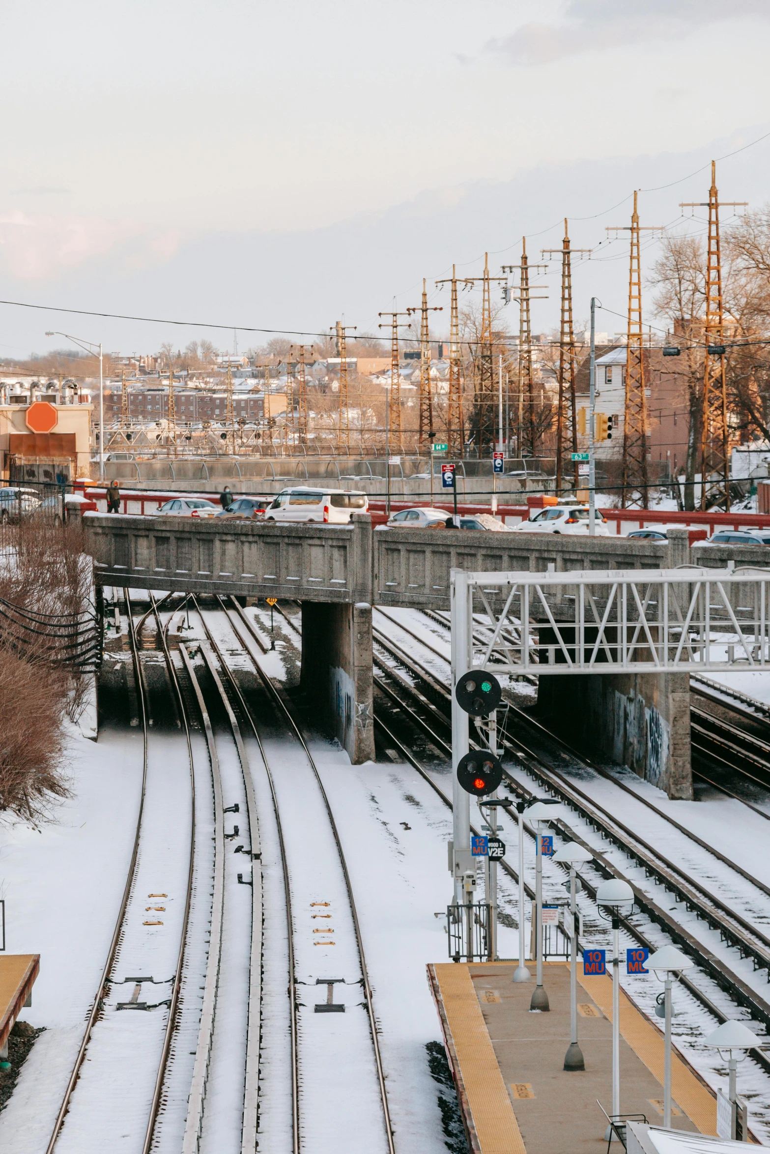 a train traveling down train tracks next to a bridge, by Greg Rutkowski, unsplash, city snowing with a lot of snow, intersection, panorama, yard