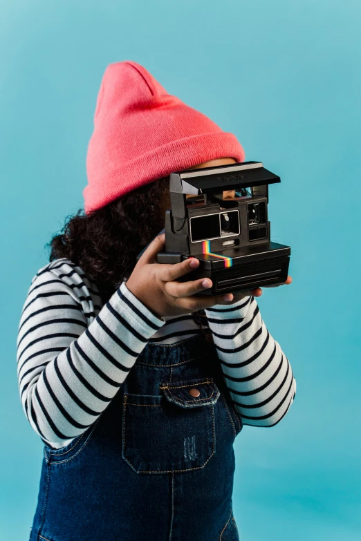 a little girl taking a picture with a polaroid camera, inspired by Wes Anderson, unsplash contest winner, hypermodernism, with black beanie on head, multicoloured, amy sol in the style of, megapixel