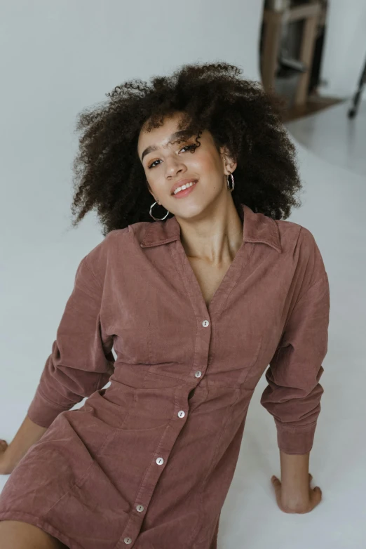 a woman sitting on the floor in a pink shirt dress, trending on pexels, renaissance, with textured hair and skin, curated collections, outfit photo, chocolate