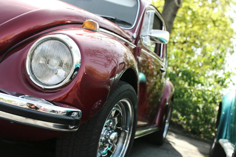 a red vw beetle parked on the side of the road, pexels contest winner, photorealism, maroon metallic accents, 1 9 7 0 s car window closeup, highly detailed wheels, sparkling in the sunlight