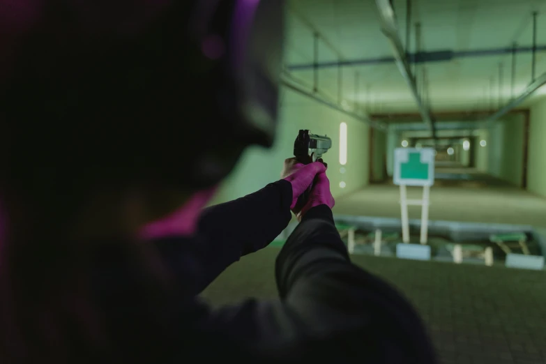 a person holding a gun in a room, immersive, technical, competition winning, over the shoulder shot