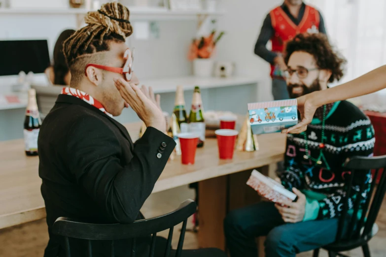 a group of people sitting around a table, holding gift, profile image, ashteroth, two men hugging