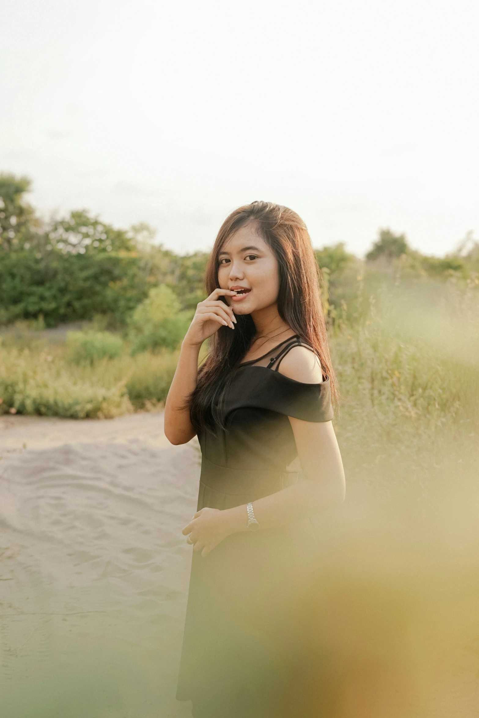 a woman standing in a field talking on a cell phone, by Yosa Buson, unsplash, realism, wearing a black shirt, beautiful asian girl, good lighted photo, smol