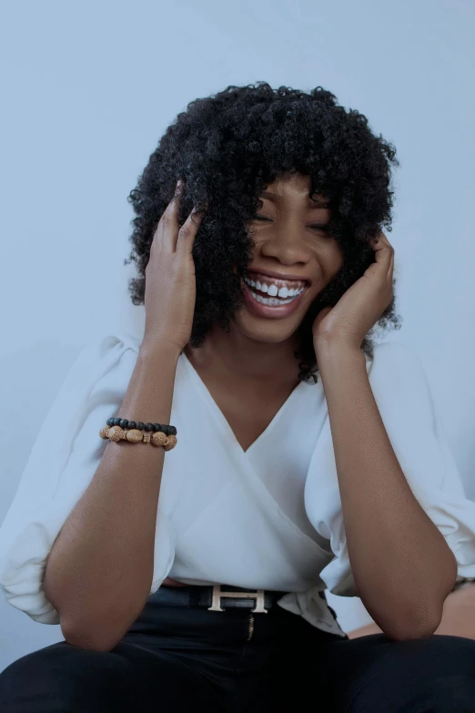 a woman sitting on a couch talking on a cell phone, an album cover, inspired by Chinwe Chukwuogo-Roy, trending on pexels, head bent back in laughter, hair is the focus, she has perfect white teeths, close - up portrait shot