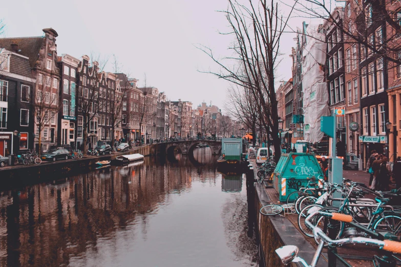 a canal filled with lots of bikes next to tall buildings, a photo, pexels contest winner, hyperrealism, 💋 💄 👠 👗, dutch houses along a river, teal aesthetic, retro haze