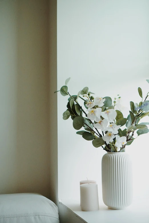 a white vase sitting on top of a window sill, a still life, unsplash, orchid stems, muted green, serene bedroom setting, detailed product image