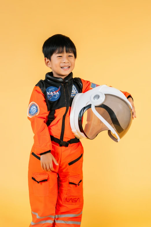 a young boy in an orange space suit holding a helmet, lulu chen, full product shot, cosmos exploration, waist up