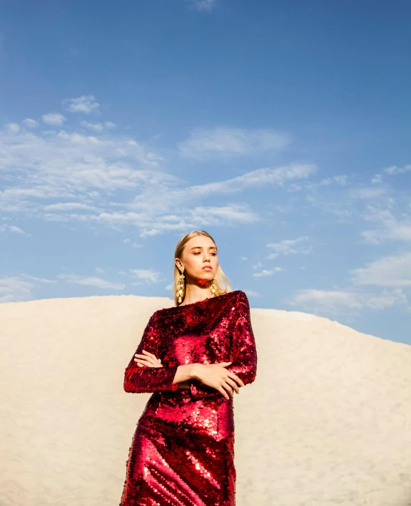 a woman in a red dress standing in the sand, by Julia Pishtar, wearing disco suit, sequins, official store photo, sydney sweeney