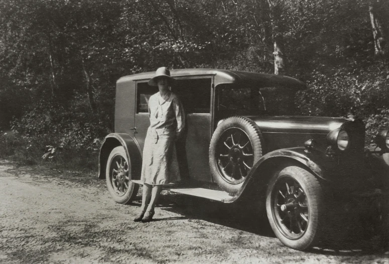 a black and white photo of a woman standing next to a car, a black and white photo, by August Sander, c. m. coolidge, vintage infrared photograph, hunting, circa 1 9 2 4