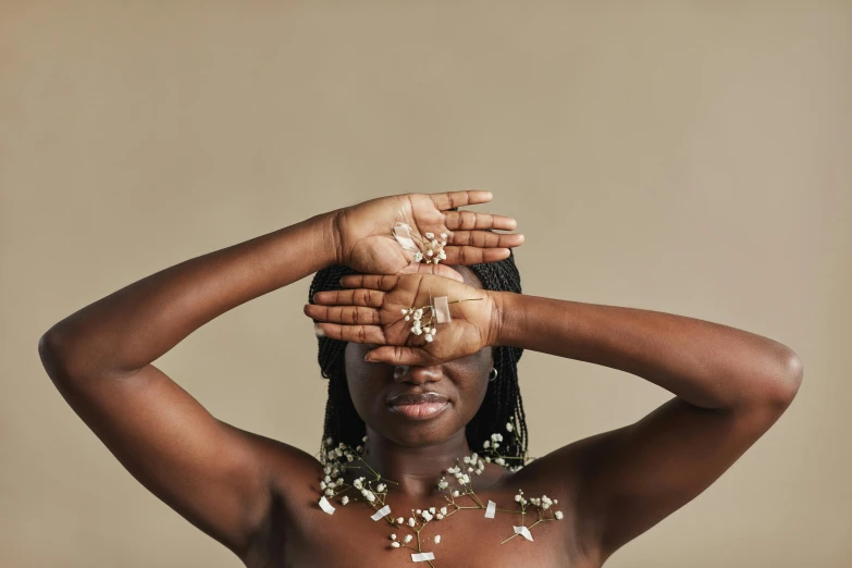 a woman covering her face with her hands, trending on pexels, afrofuturism, beads cross onbare chest, gypsophila, shrugging arms, handcrafted