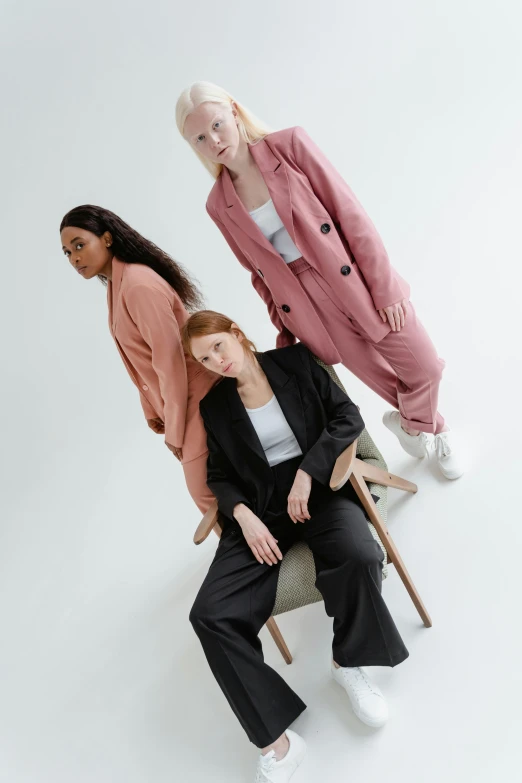 three women sitting next to each other on a chair, trending on pexels, wearing a light - pink suit, casual black clothing, creterion collection, muted colors. ue 5