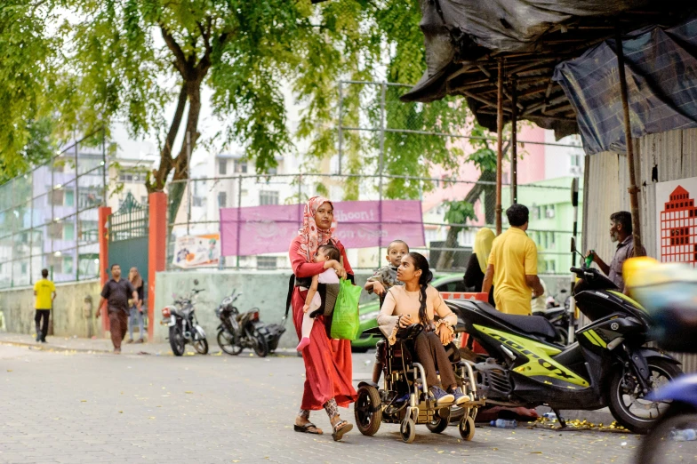 a group of people walking down a street, by Basuki Abdullah, unsplash, sumatraism, accessible for the disabled, square, families playing, zaha hadi