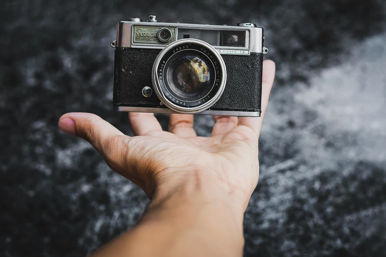 a person holding a camera in their hand, a photo of an old opened camera, high quality product image”, instagram post, canon a1