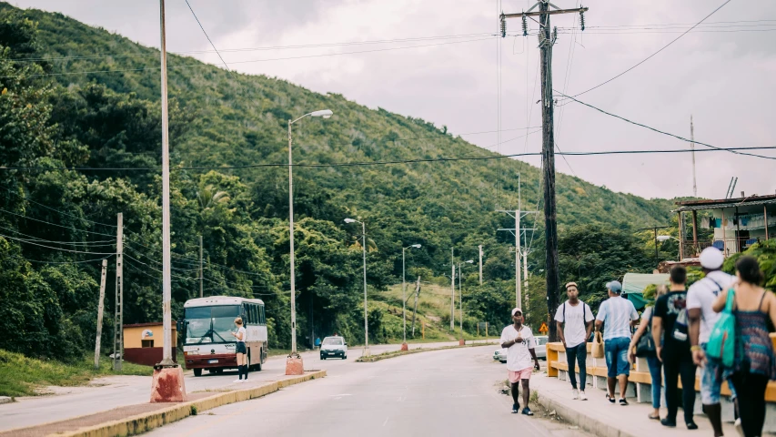 a group of people walking down a street, by Carey Morris, trending on unsplash, jamaica, hilly road, complex background, student