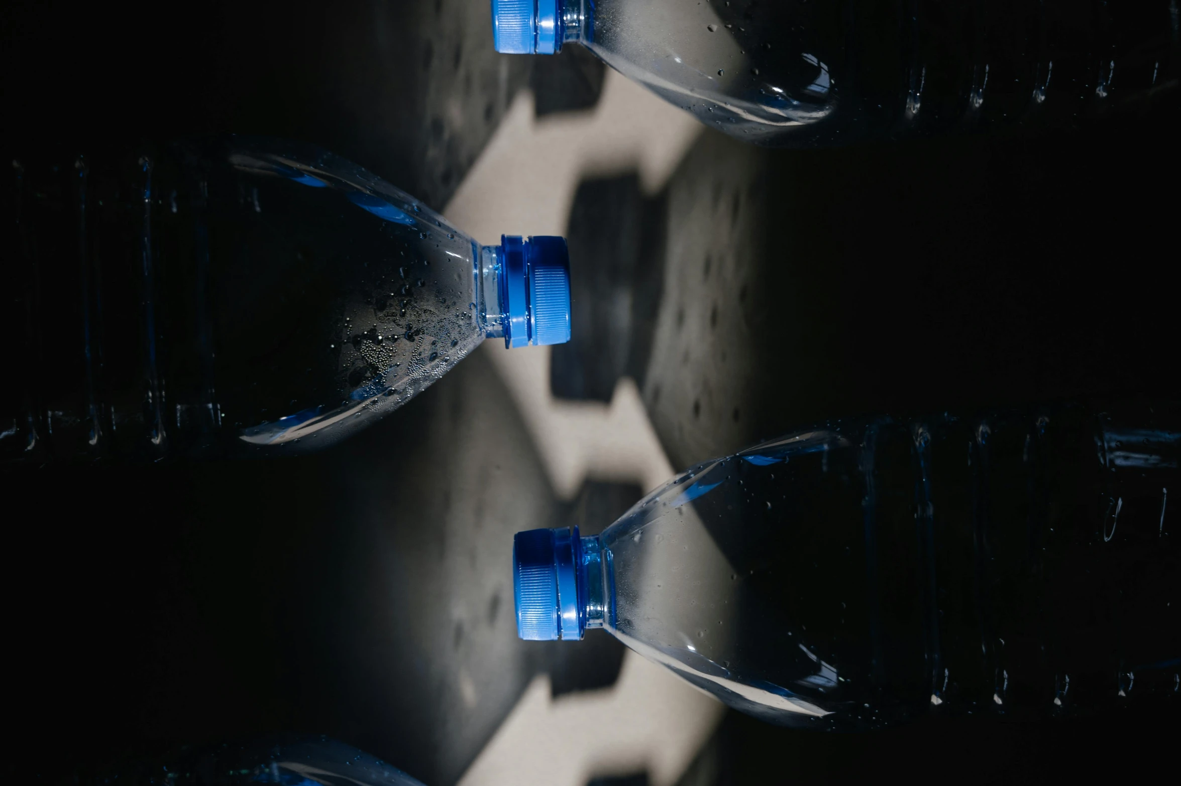 a group of water bottles sitting next to each other, by Daniel Lieske, pexels contest winner, blue-black, obscured underexposed view, thumbnail, shot on sony a 7