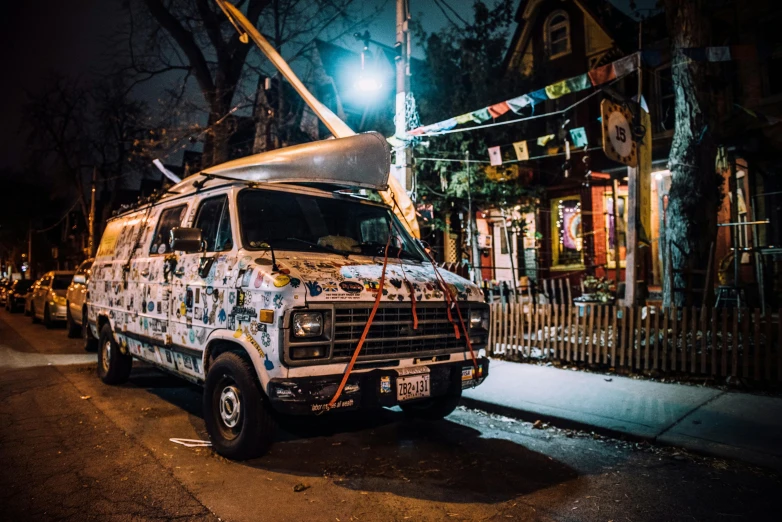 a van parked on the side of a street at night, by Julia Pishtar, pexels contest winner, graffiti, woodstock, toronto, local bar, tie-dye