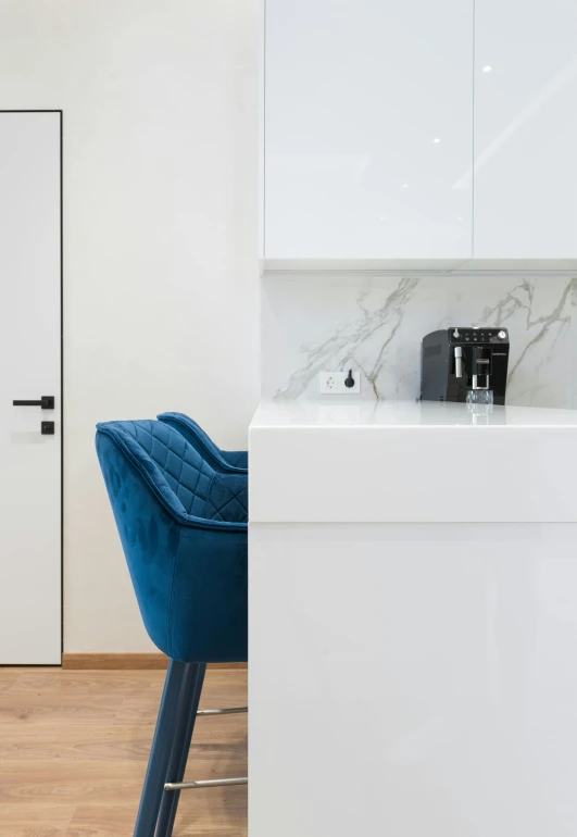 a kitchen with white cabinets and a blue chair, by Adam Marczyński, unsplash contest winner, white marble walls, office furniture, dynamic closeup, dwell