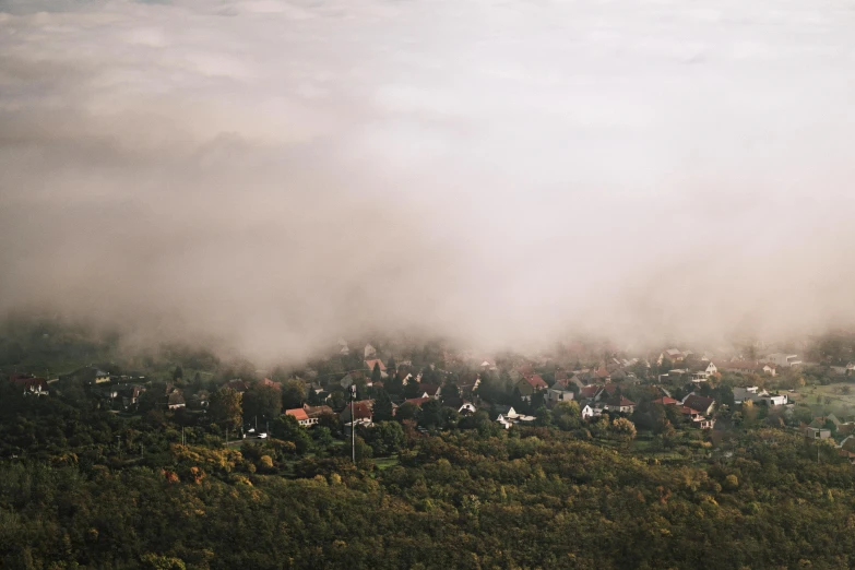 an aerial view of a town on a foggy day, pexels contest winner, “puffy cloudscape, german forest, dreamy hazy, soft light misty