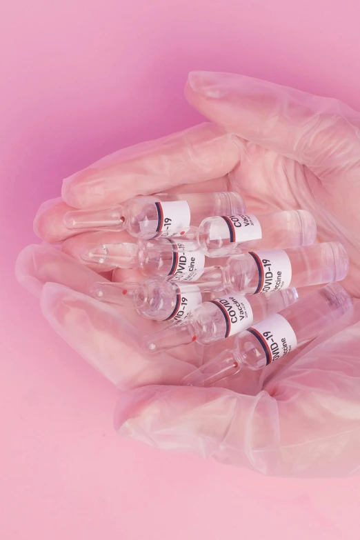 a person holding three vials in their hands, an album cover, by Nina Hamnett, pexels, plasticien, pink skin, medical labels, syringe, detailed product shot