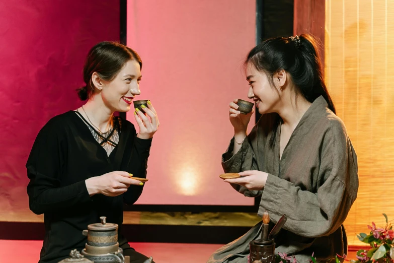 two women sitting next to each other eating food, inspired by Wang Duo, teapots, avatar image, production photo, warm and joyful atmosphere