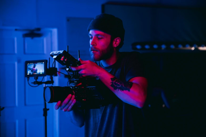 a man holding a camera in a dark room, blue and red lighting, production ig, **cinematic, b - roll