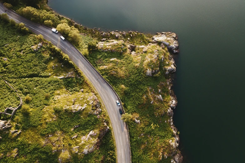 a car driving down a winding road next to a body of water, by Jesper Knudsen, pexels contest winner, birds eye, rocky roads, thumbnail, julia hetta