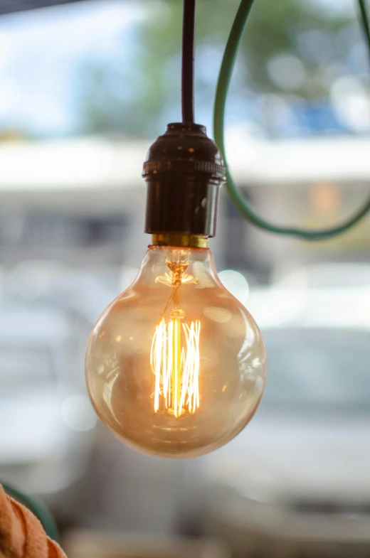 a close up of a light bulb hanging from a ceiling, on display, al fresco, edison bulb, emerging from a lamp