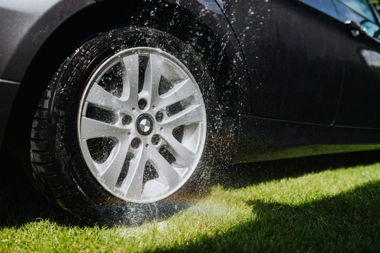 a car is sprinkled with water from a sprinkler, unsplash, auto-destructive art, detailed alloy wheels, “hyper realistic, sunny day time, tyre mark