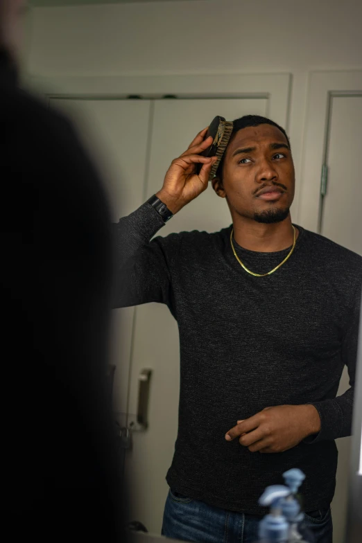 a man standing in front of a mirror brushing his hair, a photo, inspired by Theo Constanté, trending on reddit, ( ( dark skin ) ), bo burnham, taken with sony alpha 9, transgender