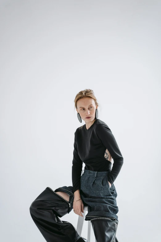 a woman sitting on top of a stool, inspired by Anna Füssli, trending on unsplash, wearing a black sweater, issey miyake, denim, model standing pose