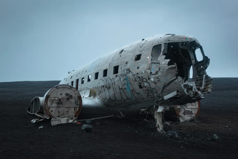 a large airplane sitting on top of a dirt field, by David Begbie, pexels contest winner, graffiti, iceland, destroyed body, dark vintage sci fi, grey