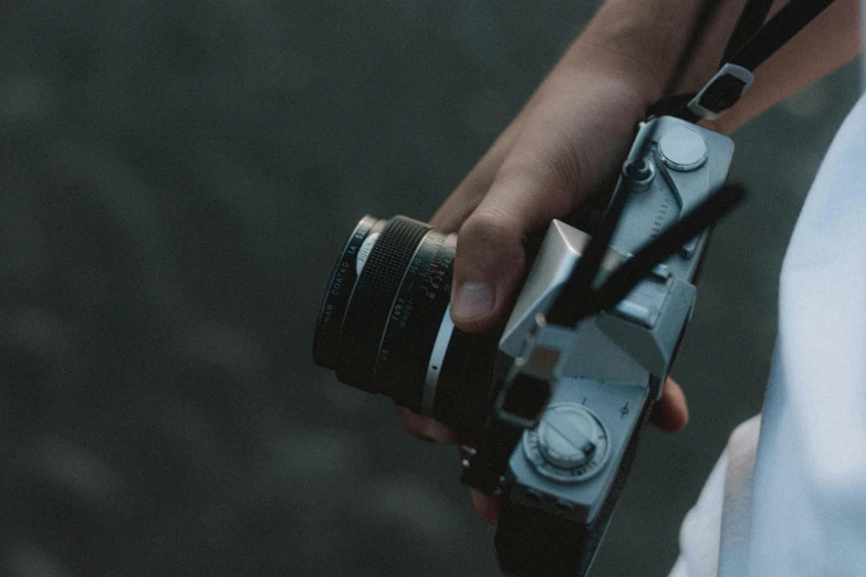 a close up of a person holding a camera, a picture, film camera, looking down on the camera, a medium shot, looking away from the camera