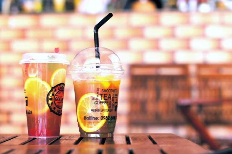 a couple of drinks sitting on top of a wooden table, pexels, photorealism, yellow and orange color scheme, hong soonsang, 2 0 0 0's photo, tea