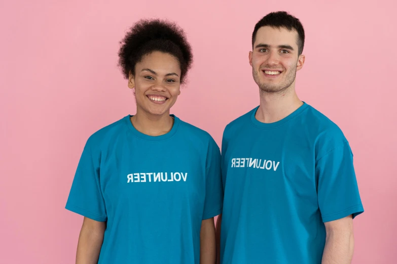 a couple of people standing next to each other, wearing a t-shirt, beautifier, teal uniform, in white lettering