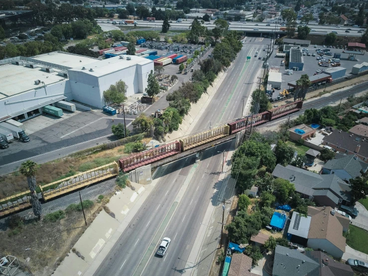 a large long train on a steel track, by Matt Cavotta, 1600 south azusa avenue, drone view of a city, huge suspended wooden bridge, 2 0 2 2 photo