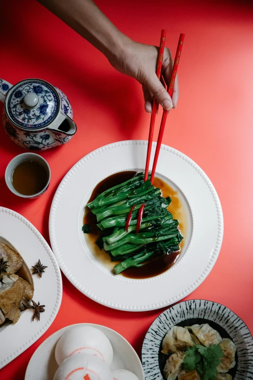 a table topped with plates of food and chopsticks, a portrait, inspired by Lu Guang, trending on unsplash, cheongsam, lush greens, profile image, made of glazed