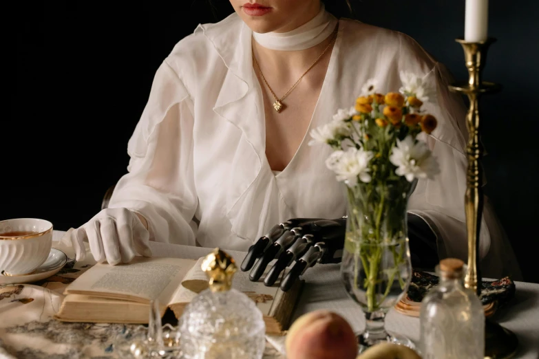 a woman sitting at a table reading a book, a still life, inspired by Hedda Sterne, trending on pexels, renaissance, collar around neck, white long gloves, dreamy mood, 1930s style clothing