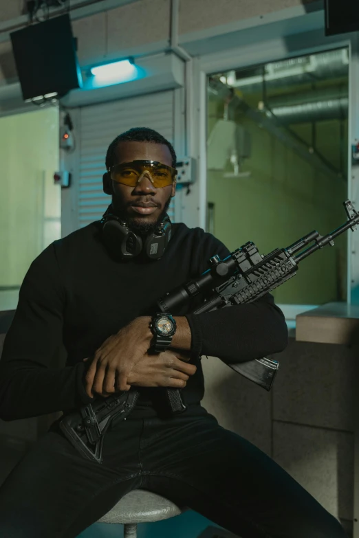 a man sitting on a stool holding a gun, jaylen brown, combat googles, stood in a lab, airsoft close quarter combat