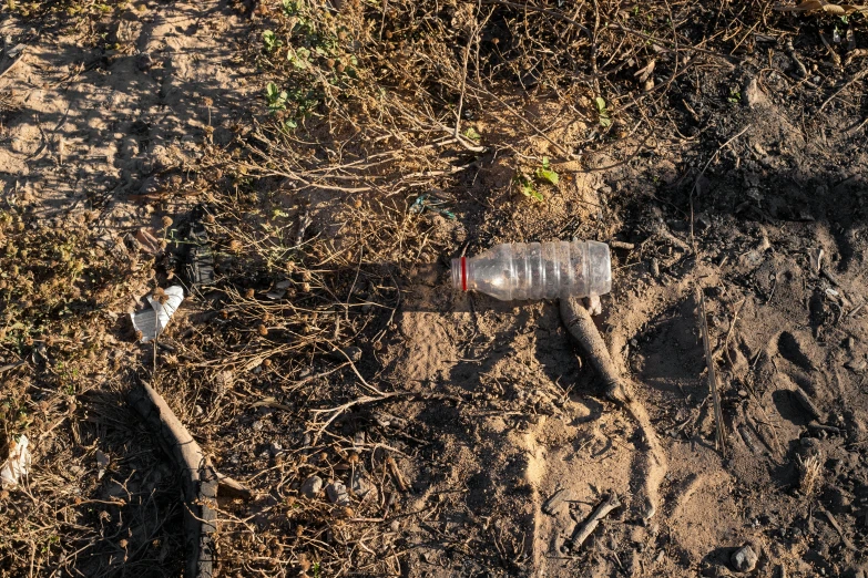 a plastic bottle sitting on top of a dirt field, broken pipes, single long stick, high quality product image”