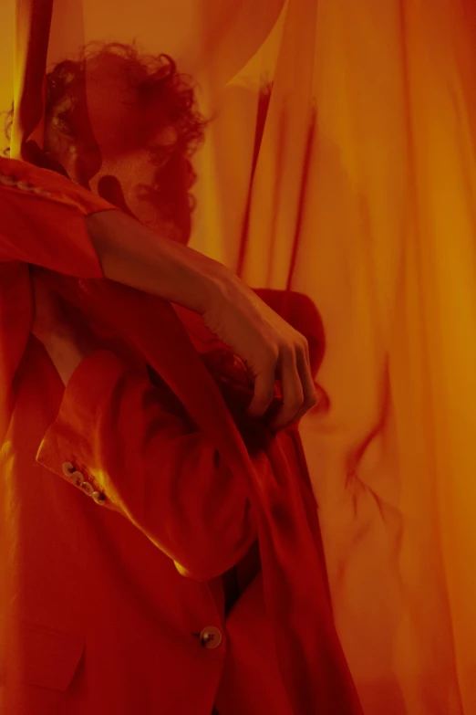 a man that is standing in front of a curtain, an album cover, inspired by Georges de La Tour, trending on pexels, orange robe, crimson red aura, showstudio, ( ( theatrical ) )