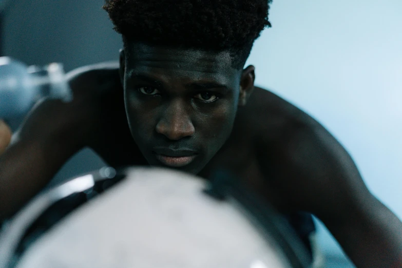 a close up of a person holding a soccer ball, inspired by Gordon Parks, pexels contest winner, afrofuturism, male model, submerged dramatic, adut akech, looking serious