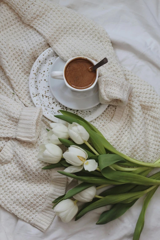 a cup of coffee and a bouquet of tulips on a bed, pexels contest winner, brown sweater, hot cocoa drink, white hue, promo image