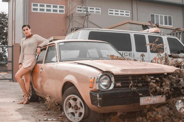 a woman standing next to an old car, an album cover, pexels contest winner, peach and goma style, gold body, demolition, brown