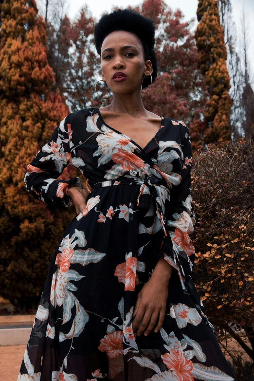 a woman in a floral dress poses for a picture, by Carey Morris, pexels contest winner, black and orange, female model, spring season, 3/4 front view