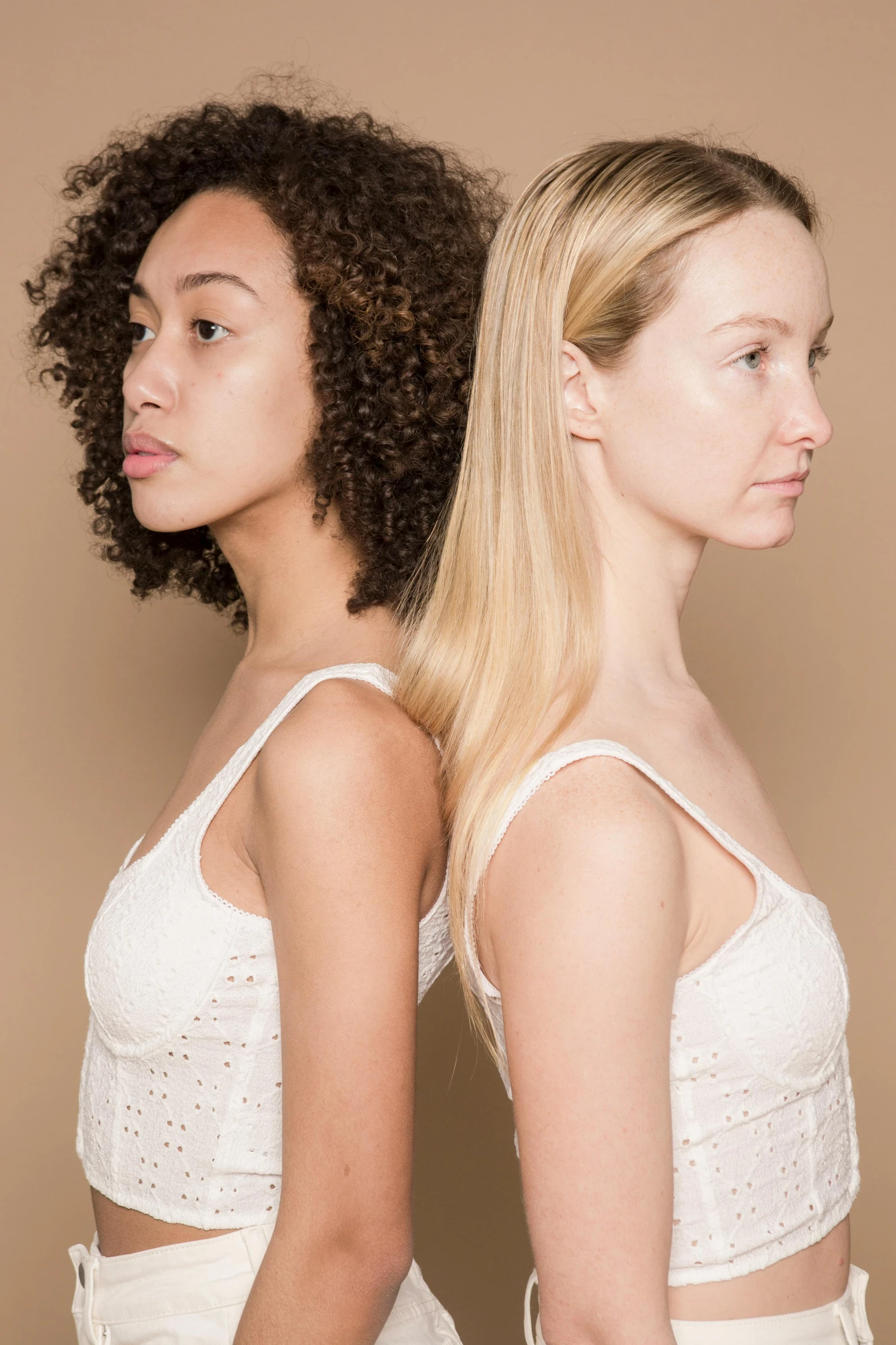 a couple of women standing next to each other, inspired by Vanessa Beecroft, trending on pexels, renaissance, gradient brown to white, halfbody headshot, mixed race, blond