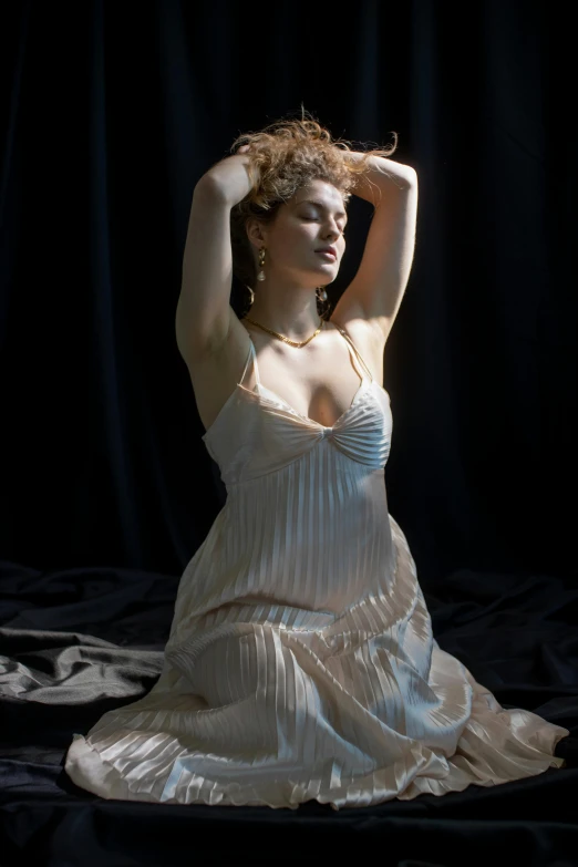 a woman in a white dress sitting on a bed, inspired by Pierre Auguste Cot, renaissance, curls and curves, in a dark studio room, photograph taken in 2 0 2 0, photorealist