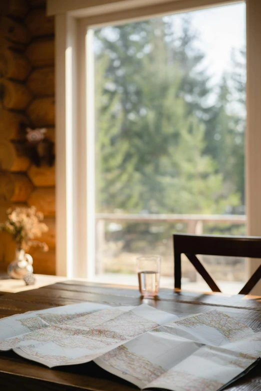 a glass of wine sitting on top of a wooden table, wide shot of a cabin interior, looking through a window frame, 2019 trending photo, whistler