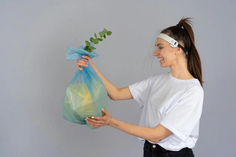 a woman holding a plastic bag with a plant in it, a hologram, by Francis Helps, dribble contest winner, plasticien, teal headband, high quality product photo, rubbish, without text