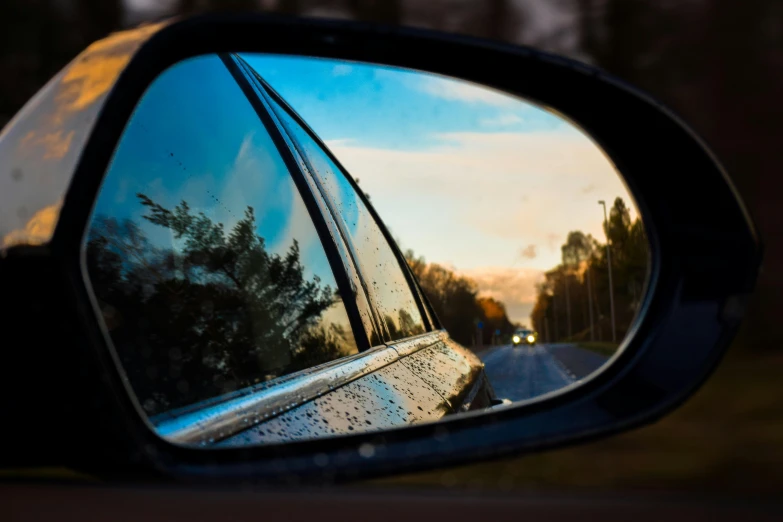 a side view mirror on the side of a car, a picture, by Thomas Häfner, unsplash, visual art, view from behind mirror, fall season, blue reflections, end of the day